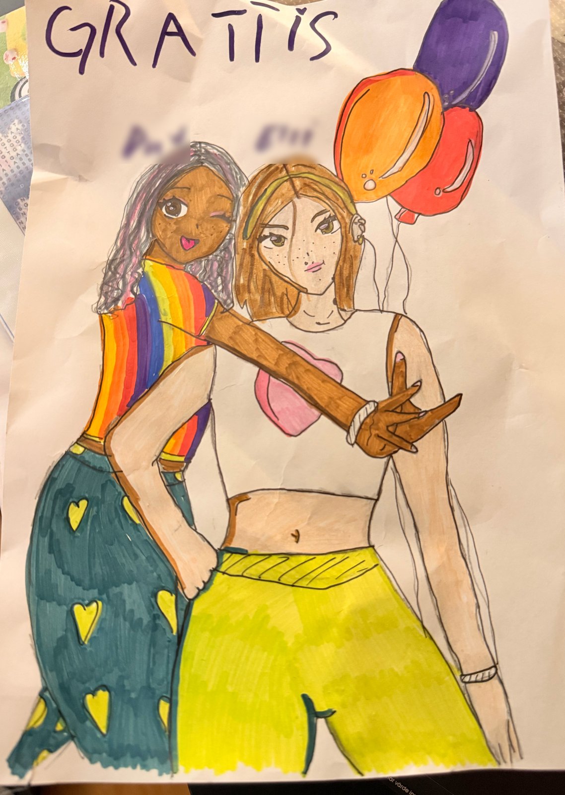 A birthday card with "GRATTIS" across the top: two smiling girls hug, one in a rainbow top and green trousers with yellow hearts, one in a white top and yellow trousers, next to orange, red and purple balloons.