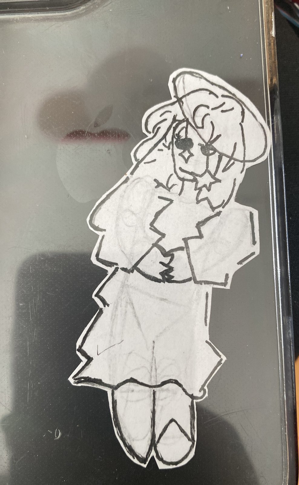 A cut-out paper girl in a hat, a jacket and a skirt, stuck inside a clear phone case.